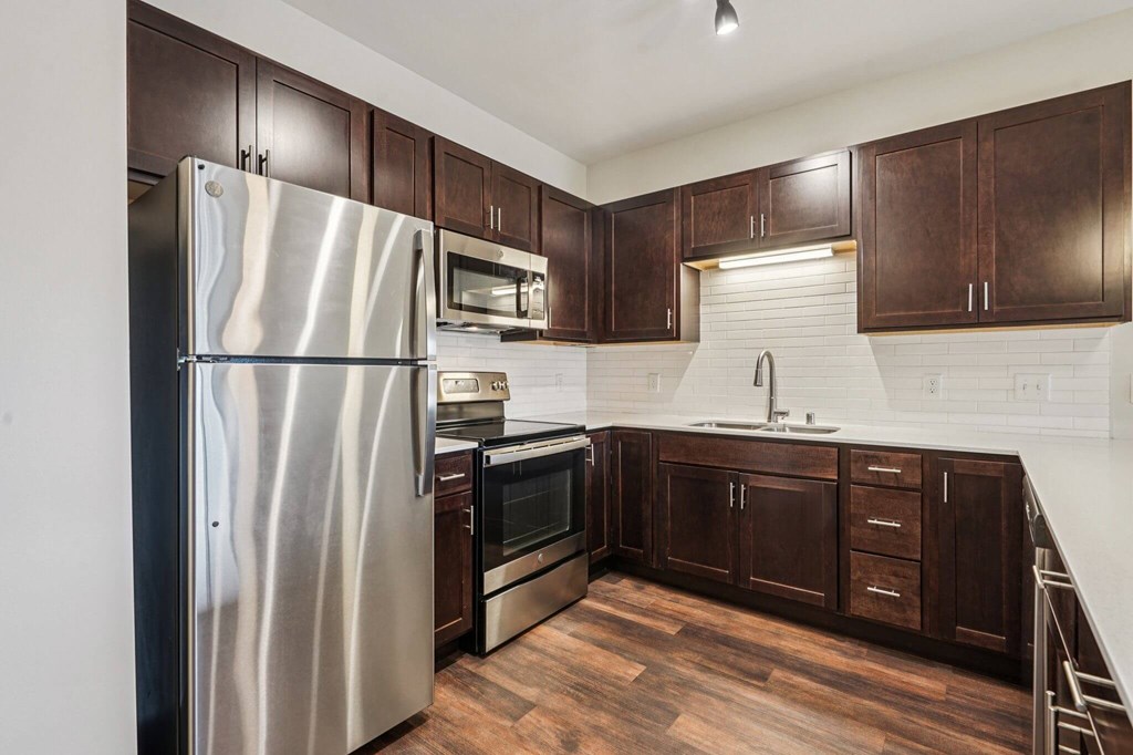 A kitchen with a stainless steel refrigerator and wooden cabinets. at Aster Meadow, Minnesota, 55127