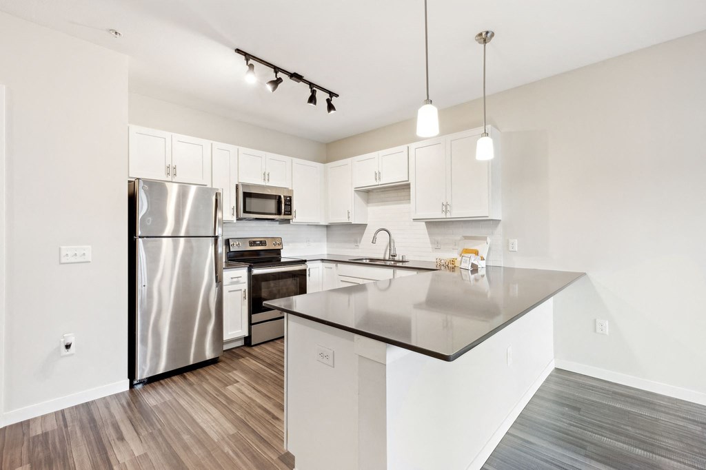 A modern kitchen with a stainless steel refrigerator and a black granite countertop. at Aster Meadow, Vadnais Heights, MN