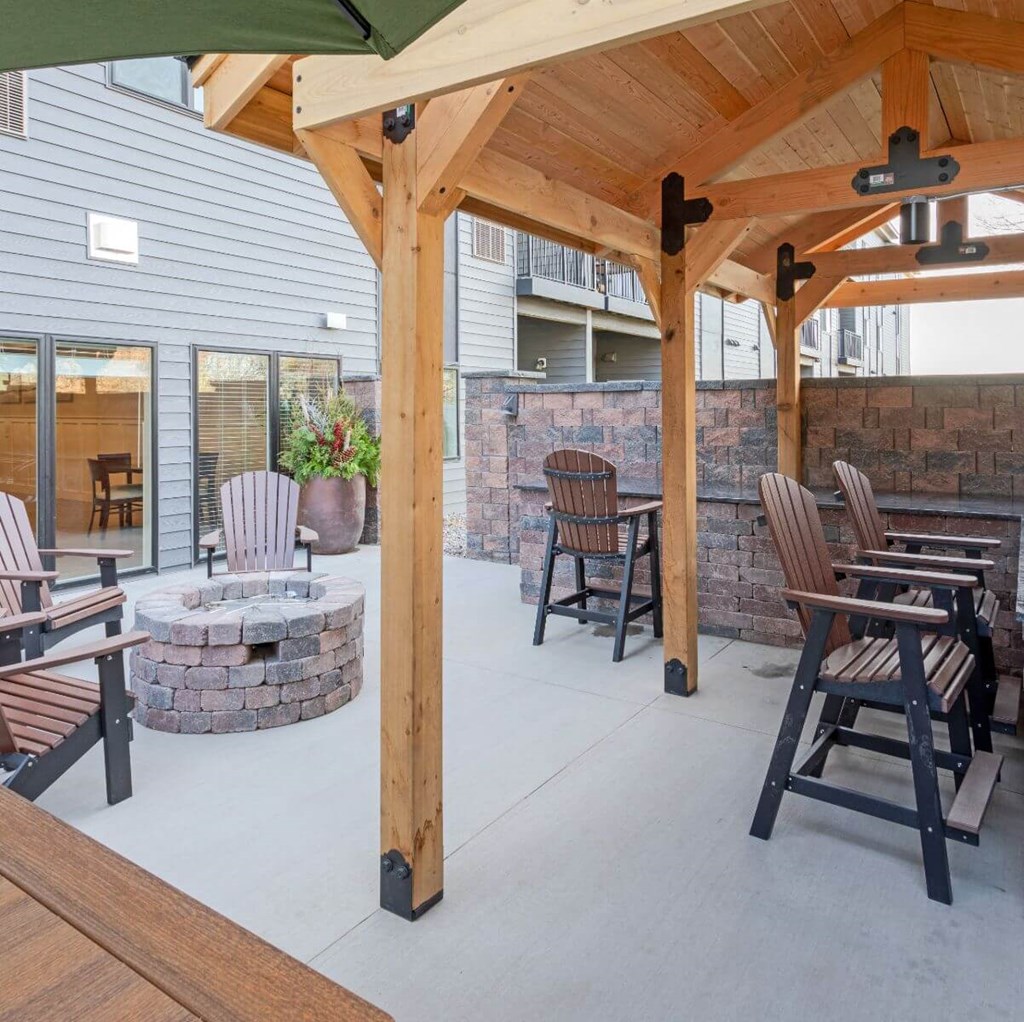 A wooden patio with a fire pit and chairs. at Aster Meadow, Minnesota, 55127