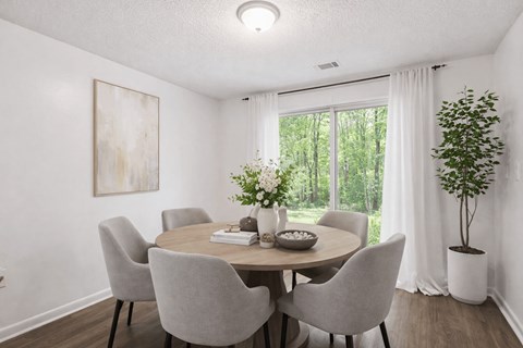 A dining room with a round table and grey chairs.