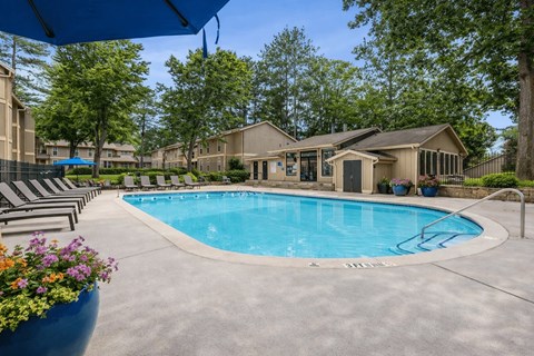 Outdoor swimming pool with lounge chairs and clubhouse at Linden Ridge Apartments, Stone Mountain