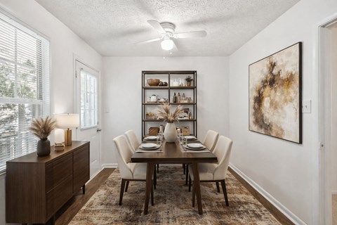 A dining room with a table set for six and a painting on the wall at Emerald Pointe, Riverdale, GA