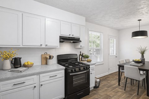 A kitchen with a black stove top oven and white cabinets.