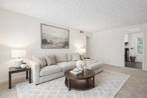A living room with a white couch, a coffee table, and a painting on the wall.