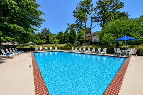 A large swimming pool surrounded by trees and chairs.
