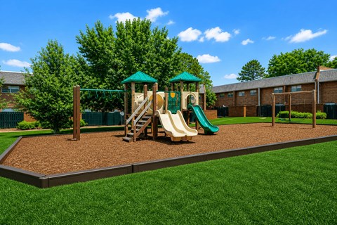 A playground with a green slide and a wooden swing set.