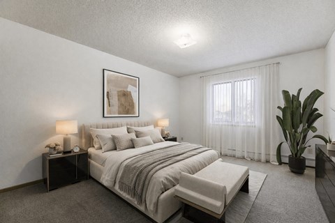 A bedroom with a large bed and a potted plant.