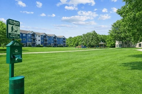 A sign in a grassy area indicates a pet waste disposal area.