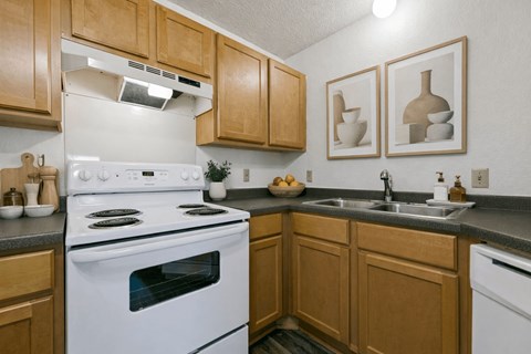 A kitchen with wooden cabinets and a white stove top oven.