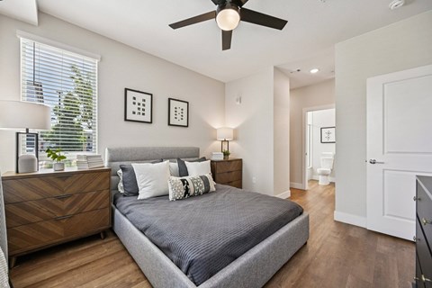 Bedroom with gray upholstered bed and ceiling fan at Sequel Homes Apartments, Englewood, Colorado