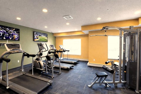 Fitness center with cardio equipment and tvs at Cypress Court Apartments, St Cloud, MN