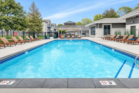 Outdoor swimming pool with sundeck and lounge chairs at Prosper West Apartments, Waite Park, Minnesota