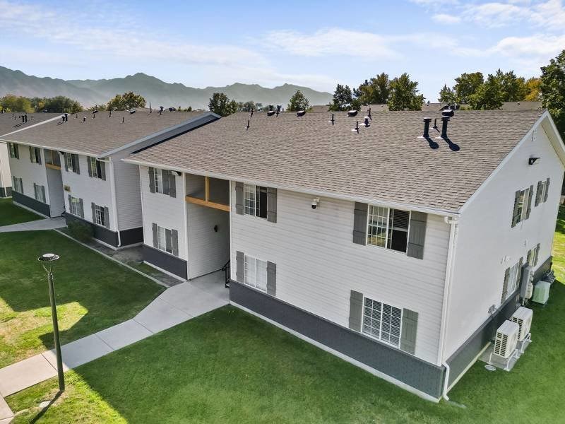A white apartment building with a green lawn in front at Lexington Park Apartments, Utah, 84119