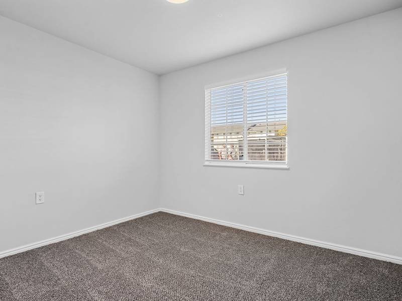 A room with a carpeted floor and a window with blinds at Lexington Park Apartments, West Valley City, UT 84119