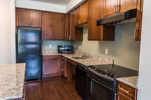 A kitchen with wooden cabinets and a black fridge.