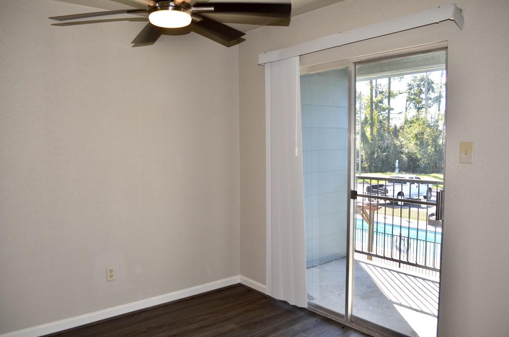 A room with a ceiling fan and sliding glass doors leading to a pool and trees. A room with a ceiling fan and sliding glass doors leading to a pool and trees at The Wilshire Apartment, Louisiana