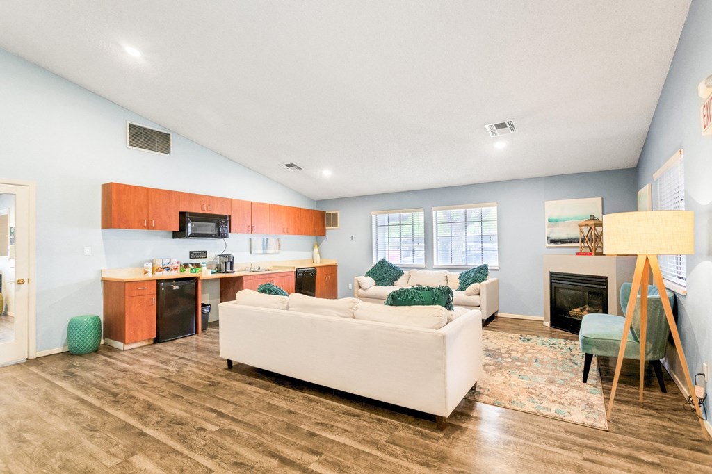 a living room with a couch a chair and a kitchen with a stove and microwave