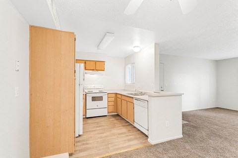 an empty kitchen with white appliances and wood floors
