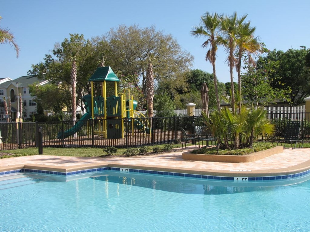 a swimming pool with a playground in the background