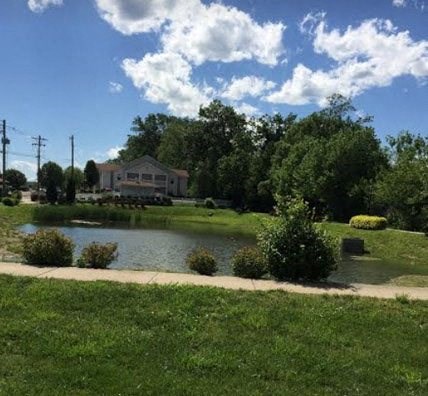 a pond in a park with a house in the background