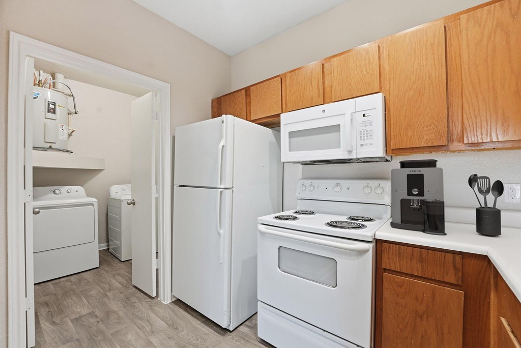 A kitchen with white appliances and wooden cabinets.