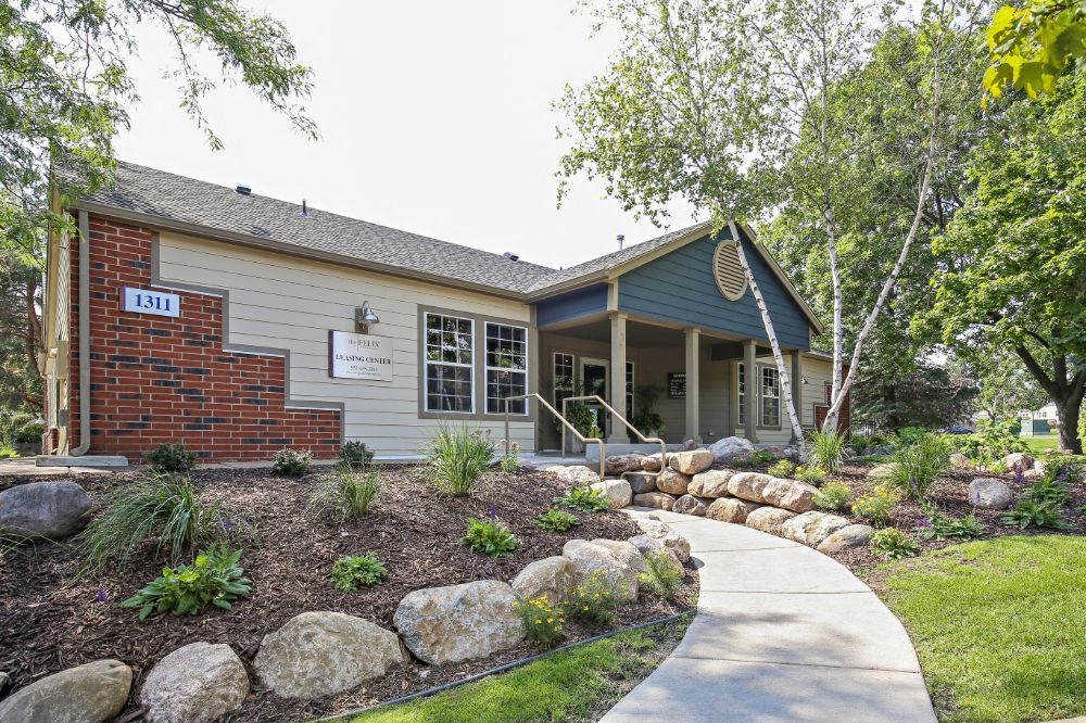the front of a building with a sidewalk and landscaping