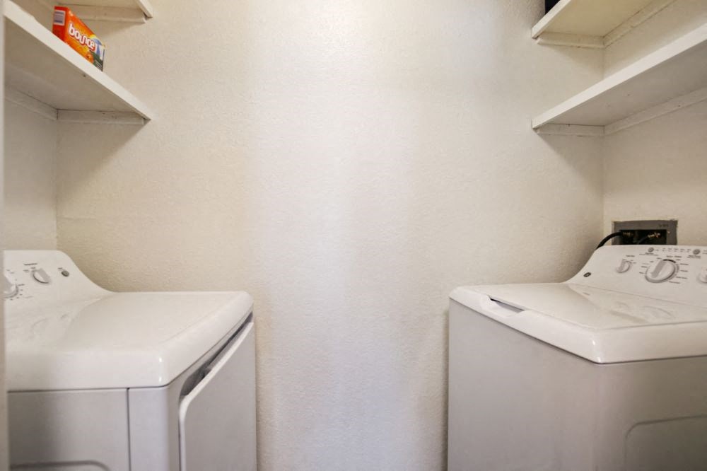 a white laundry room with two washes and a dryer