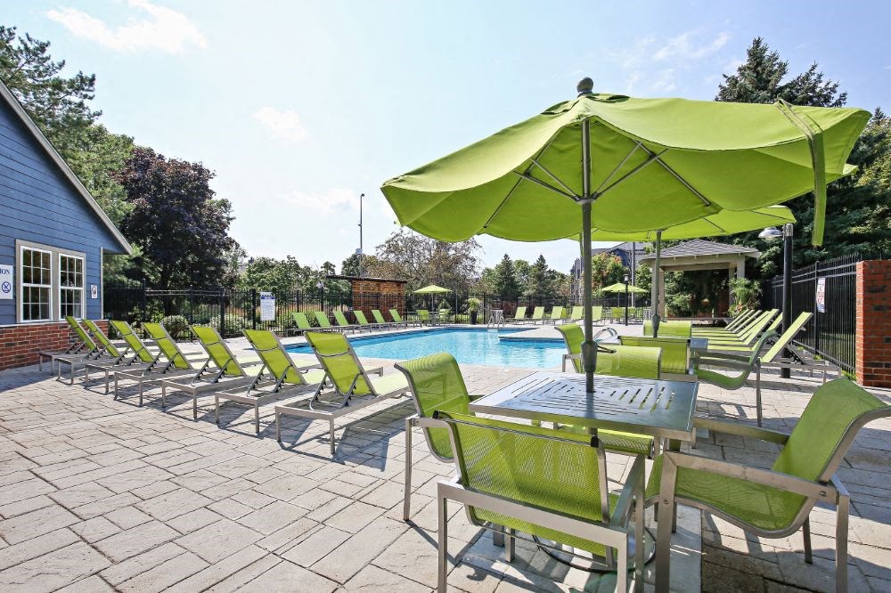 a pool with green chairs and a table with an umbrella