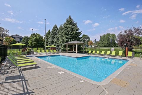 a swimming pool with green lounge chairs around it