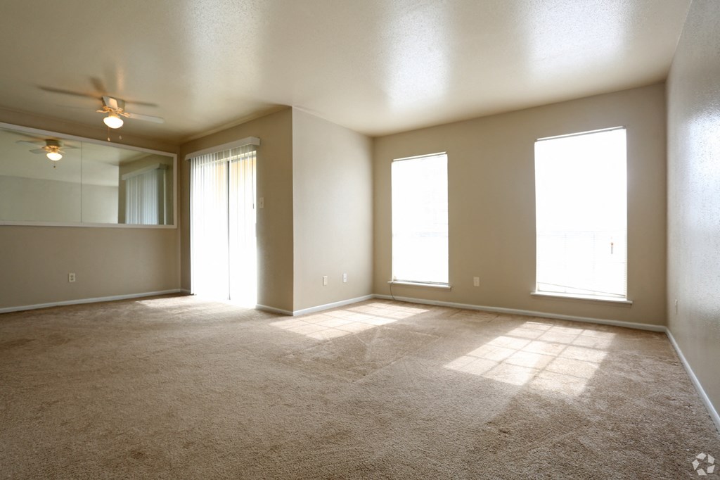 an empty living room with a ceiling fan