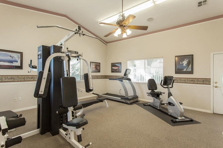 a gym with exercise equipment and a ceiling fan