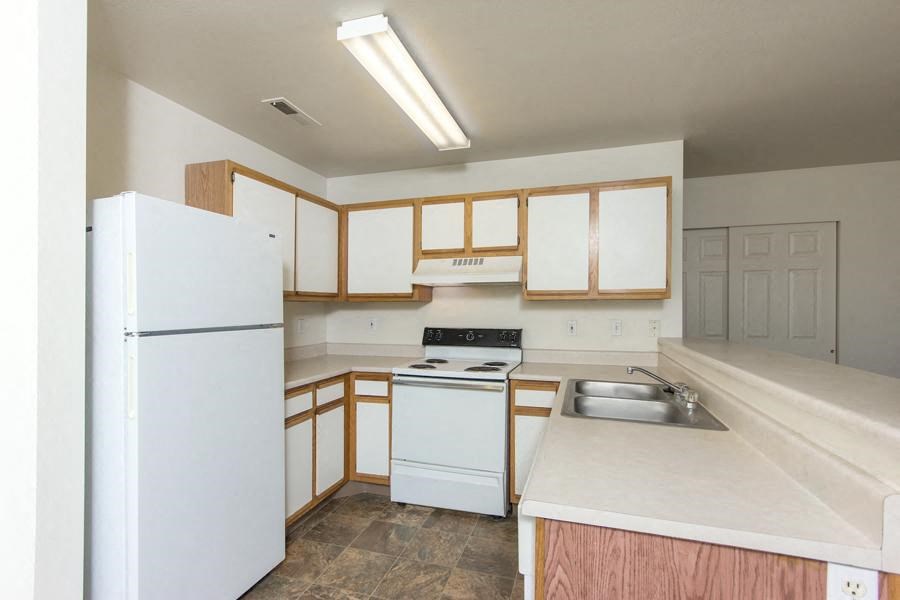 an empty kitchen with white appliances and wooden cabinets