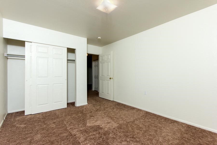 an empty living room with white walls and a door to a closet
