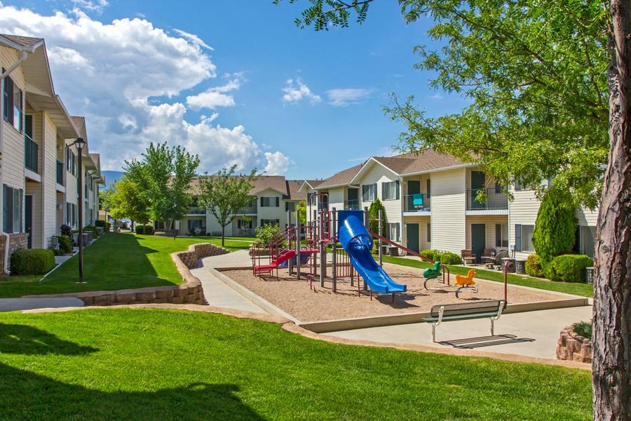 a playground with a blue slide in front of apartments