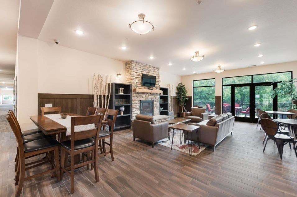 A modern dining room with a fireplace and wooden floors. at Lake Ridge Apartments, Prior Lake