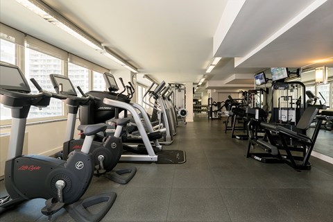A gym with a variety of equipment including treadmills, stationary bikes, and weight machines.