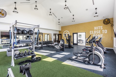 A gym with a green floor and a yellow wall that says "Hits Close to Home.".