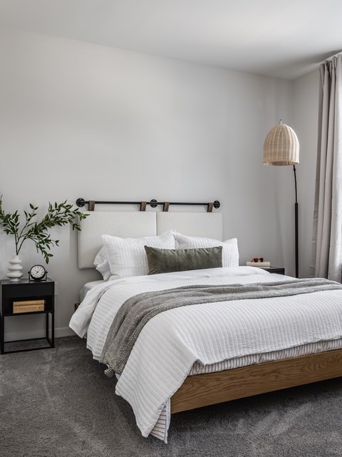 A bedroom with a large bed and a nightstand with a plant on it.