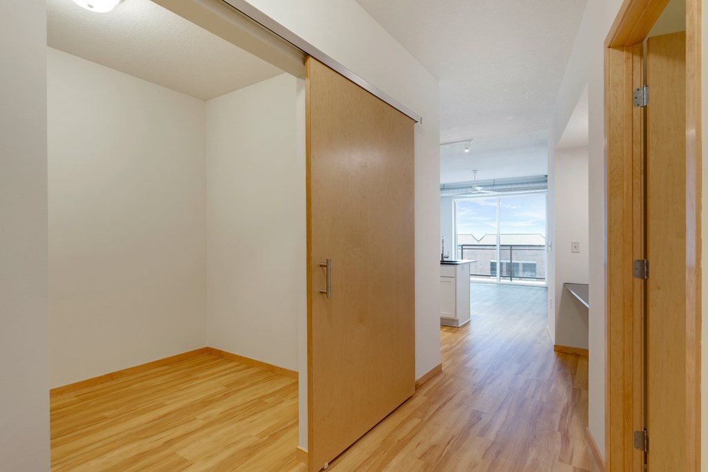 A hallway with a wooden floor and white walls.