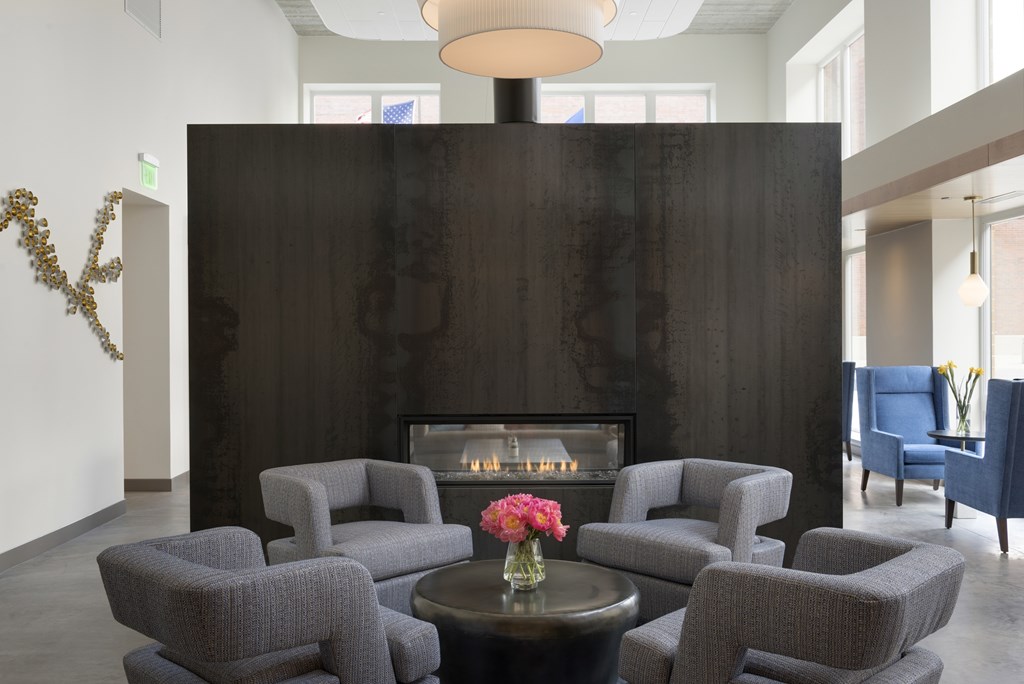 A living room with a fireplace and grey chairs.