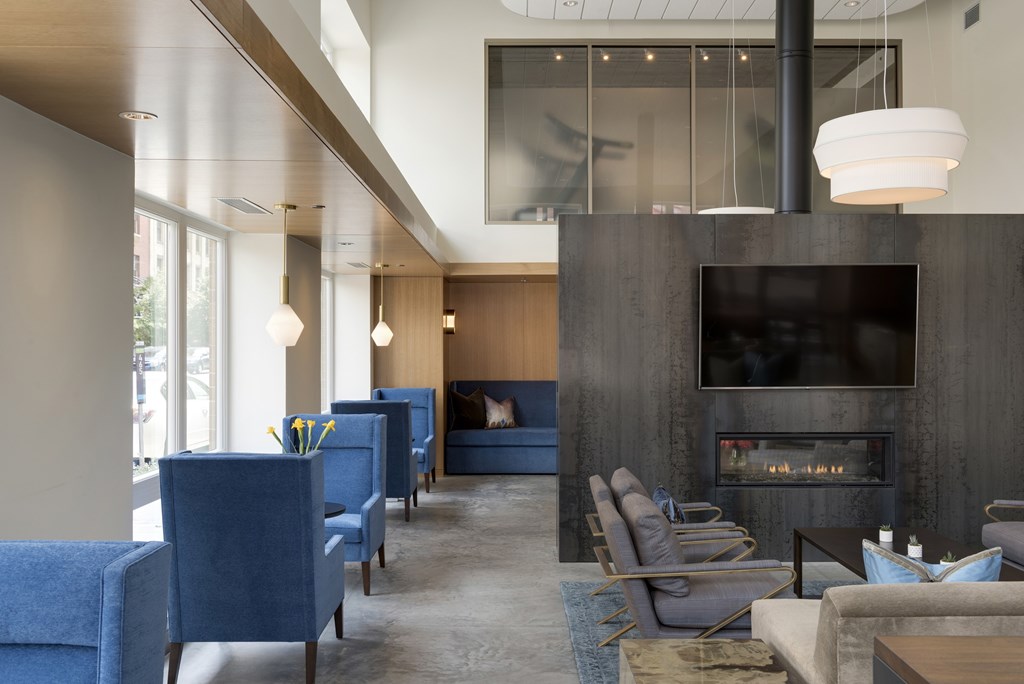 A modern living room with a fireplace and blue chairs.