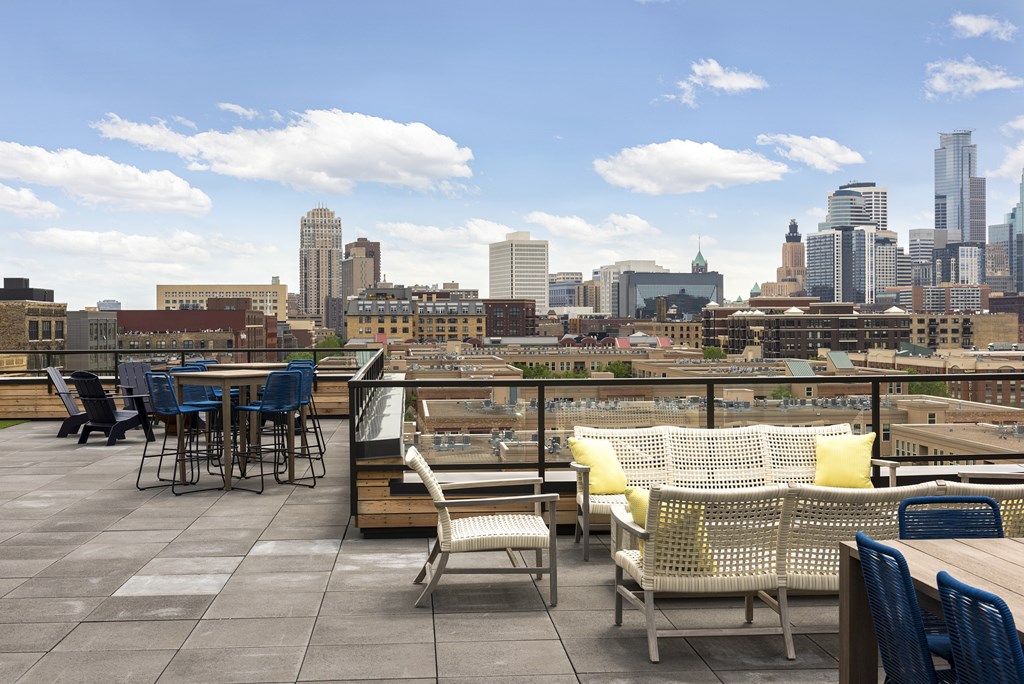A rooftop patio with a table and chairs overlooking a city skyline.