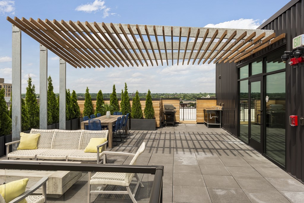 A patio with a wooden pergola and outdoor furniture.