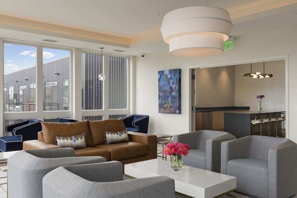 A living room with a grey couch, a brown couch, a white coffee table, and a large window.