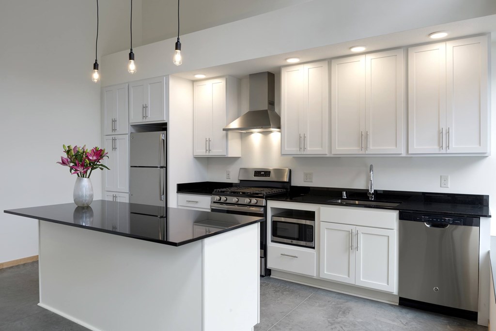 A modern kitchen with white cabinets and black countertops.