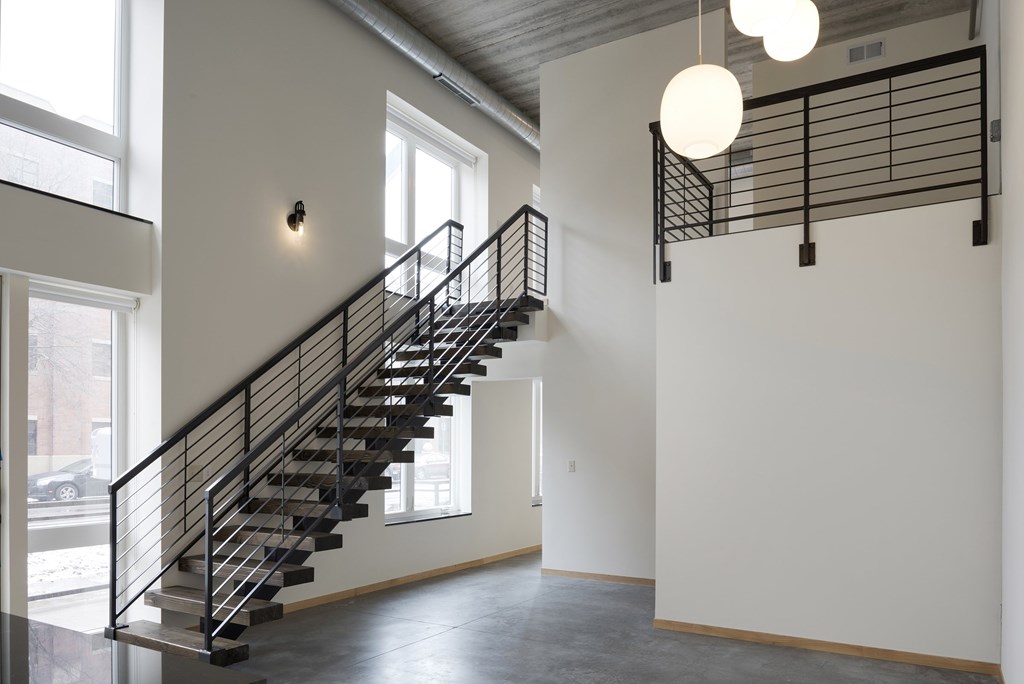 A staircase with a metal railing and a light hanging from the ceiling.