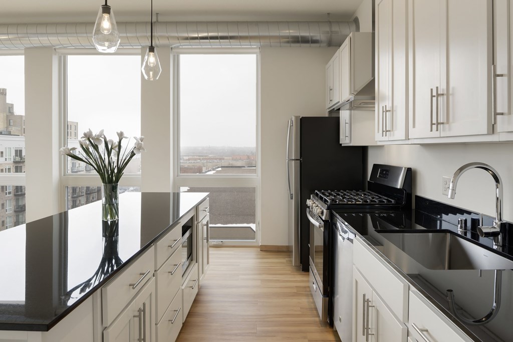A modern kitchen with black countertops and white cabinets.