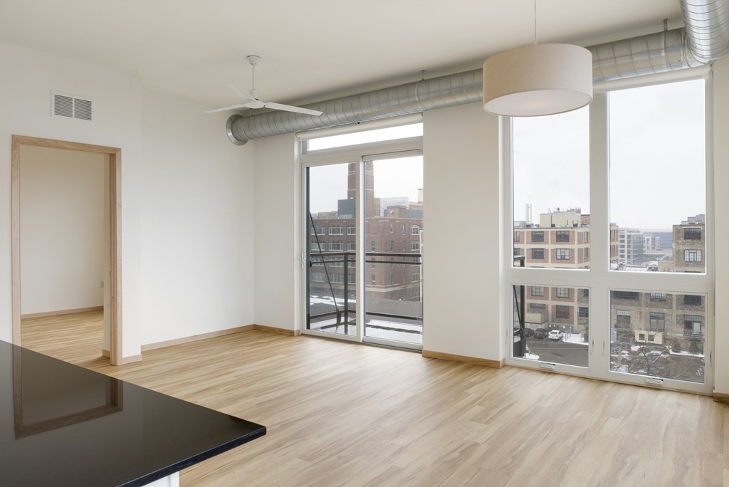 A room with a black table and a view of the city through the windows.