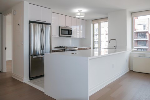 A modern kitchen with white cabinets and a stainless steel refrigerator.