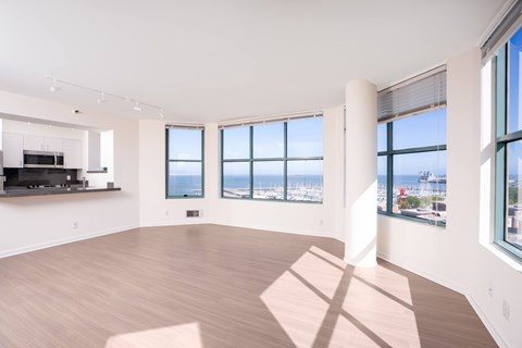 A spacious room with wooden floors and large windows overlooking a cityscape.